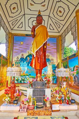 PAI, THAILAND - MAY 6, 2019: Interior of the shrine of Wat Pa Kham temple with a statue of Standing Buddha with painted walls and ceiling around it, on May 6 in Pai