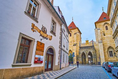 PRAGUE, CZECH REPUBLIC - MARCH 6, 2022: Lazenska Street of Lesser Quarter opens the view on the medieval gate and bell towers of Johannite Monastery, on March 6 in Prague