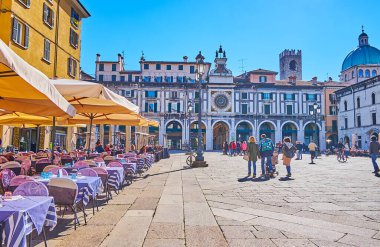 BRESCIA, ITALY - APRIL 10, 2022: Historic building with arcades and richly decorated Torre dell'Orologio (Clock Tower) with astronomical clock, located on Piazza della Loggia square, on April 10 in Brescia