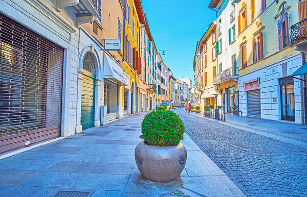 The narrow curved Via della Pace street, lined with colored histroic buildings, Brescia, Italy
