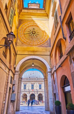 The medieval scenic Torre dell'Orologio astronomical clock from Via Cesare Beccaria street with Loggia Palace, seen through the arch, Brescia, Italy