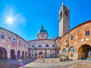 Panoramic view of Palazzo Broletto courtyard with Torre del Pegol clocktower, stone fountain and dome of New Cathedral in background, Brescia, Italy