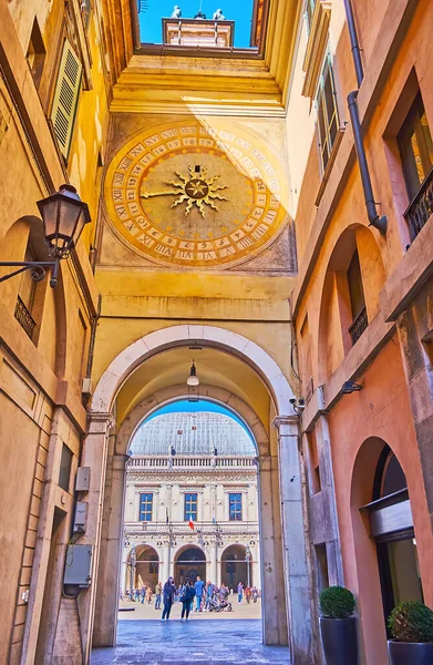 The medieval scenic Torre dell'Orologio astronomical clock from Via Cesare Beccaria street with Loggia Palace, seen through the arch, Brescia, Italy