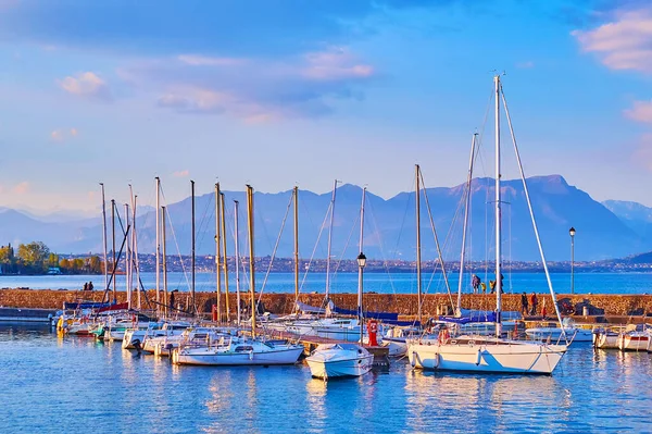 The yacht port on Lake Garda with azure water surface and foggy Garda Prealps in background, Desenzano del Garda, Lombardy, Italy