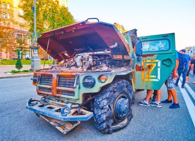People explore bombed and burnt Tigr multipurpose all-terrain infantry mobility vehicle on the exhibition of destroyed Russian military equipment , Kyiv, Ukraine
