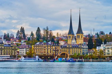 LUCERNE, SWITZERLAND - MARCH 30, 2022: The spires of Church of St. Leodegar and Nationalquai embankment, on March 30 in Lucerne, Switzerland