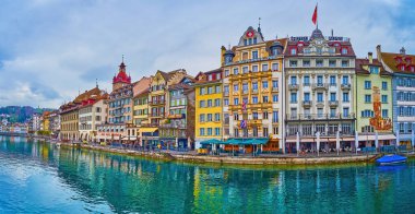 LUCERNE, SWITZERLAND - MARCH 30, 2022: Panoramic view on Altstadt's embankment of Reuss river with colorful medieval buildings, on March 30 in Lucerne, Switzerland