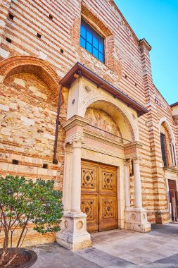 The carved stone gate of San Giovanni Evangelista Church with white columns and a fresco, Brescia, Italy