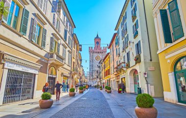 Historic Corso Giuseppe Garibaldi street with lines of historic buildings and Pallata Tower in background, Brescia, Italy