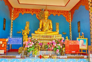 MAE HONG SON, THAILAND - MAY 6, 2019: The colored interior of the shrine of Wat Phrathat Doi Kong Mu with golden images of Buddha and lotus flowers, on May 6 in Mae Hong Son