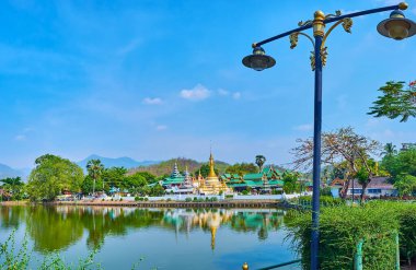 The green park and Buddhist Temples around the mirror-like Nong Kham Lake, Mae Hong Son, Thailand
