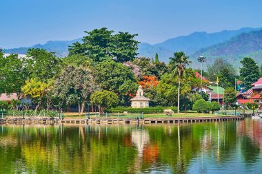 The tropical green park and carved Singha statue on embankment of Nong Kham Lake, architecture, Mae Hong Son, Thailand