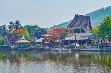 The lush greenery and bright blooming flame trees in front of Nong Kham Lake, Mae Hong Son, Thailand