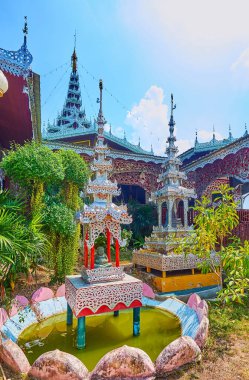 The richly decorated mini shrines with multi-tired (pyathat) roofs in garden of Wat Chong Kham Temple, Mae Hong Son, Thailand