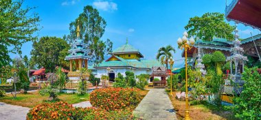 The beautiful blooming tropic garden with ornate shrines and viharns of Wat Chong Kham Temple, Mae Hong Son, Thailand
