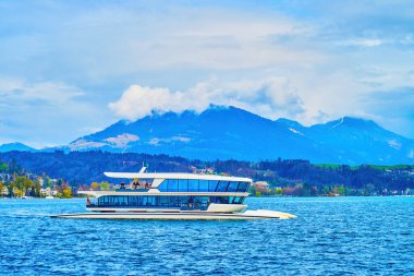 Modern catamaran sails along the Bay of Lucerne in surrounding of Alps mountains, Switzerland