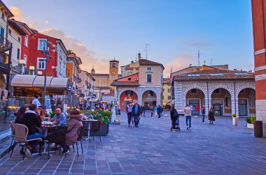 DESENZANO DEL GARDA - 10 Nisan 2022: Akşam Piazza Giuseppe Malvezzi kalabalık restoran ve bar terasları ile, 10 Nisan 'da Desenzano del Garda' da