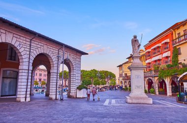 DESENZANO DEL GARDA, ITALY - 10 Nisan 2022: 10 Nisan 'da Desenzano del Garda' da tarihi evleri, kafeleri ve anıtı bulunan gün batımı Piazza Giuseppe Malvezzi meydanı