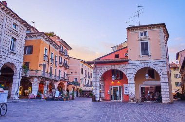 Eski turist Piazza Giuseppe Malvezzi meydanında, renkli evleri, hediyelik eşya dükkanları ve açık hava restoranları olan Desenzano del Garda, İtalya 'nın tadını çıkarın.