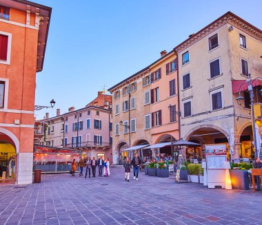 DESENZANO DEL GARDA, ITALY - 10 Nisan 2022: Piazza Giuseppe Malvezzi Meydanı, açık hava restoranları terasları ve eski püskü tarihi evler serisi, 10 Nisan 'da Desenzano del Garda