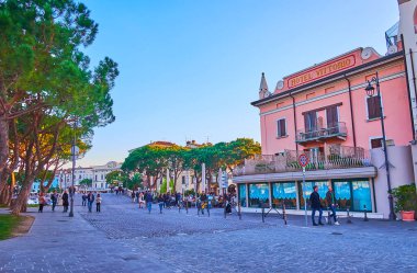 DESENZANO DEL GARDA - 10 Nisan 2022: Tarihi evleri ve yüksek çamları olan Porto Vecchio üzerinden 10 Nisan 'da Desenzano del Garda' da