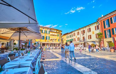 SIRMIONE, İTALYA - 10 Nisan 2022: 10 Nisan 'da Sirmione' de büyük yaya meydanı Giosue Carducci renkli binalar ve yerel kafe ve restoranların terasları ile çevrilidir.