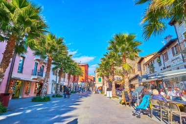 SIRMIONE, İTALYA - 10 Nisan 2022: 10 Nisan 'da Sirmione' de renkli evleri, restoranları, kafeleri ve uzun palmiye ağaçları olan manzaralı Piazza Flaminia