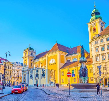 VIENNA, AUSTRIA - 17 Şubat 2019 'da Avusturya' nın Viyana kentinde Freyungplatz meydanı ve Schottenkirche kilisesi üzerindeki Avusturya fıskiyesi