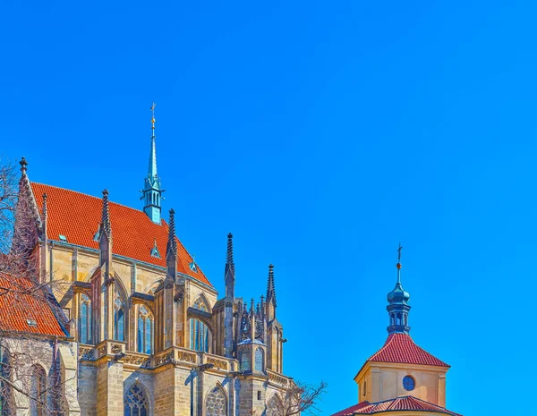 在捷克共和国科林市 圣巴多罗缪教堂的支柱顶上的屋顶和雕刻的石塔以及教区学校的穹顶与明亮的蓝天相映成趣 — 图库照片