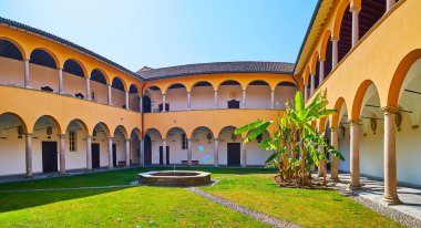 Collegio Papio 'nun tarihi avlusunun panoramik manzarası yeşil çimlerin ortasında eski bir taş çeşme, Ascona, İsviçre