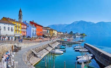 Piazza Giuseppe Motta 'daki tarihi renkli kasaba evleri, İsviçre, Ascona' da bulunan küçük tekneleriyle Maggiore Gölü 'ne bakıyor.
