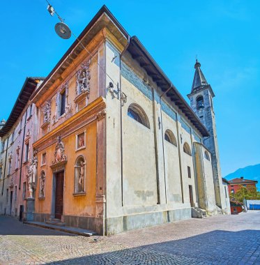 Santa Maria Assunta Kilisesi 'nin köşesinde ince taş çan kulesi, heykeller ve şekiller var.