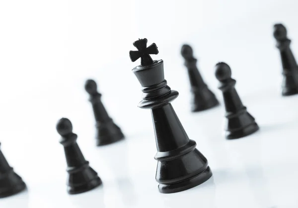 Black King chess in front of team over white background — Stock Photo, Image