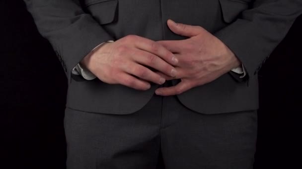 Een jonge zakenman in een pak doet zijn trouwring uit en stopt hem in zijn zak. De taille van een man close-up op een zwarte achtergrond. — Stockvideo