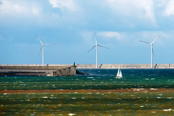 Seascape with a sailboat and a wind farm on rough sea — Stock Photo, Image