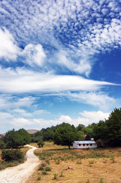 Cabine in de berg met een weg en een mooie cloudscape — Stockfoto