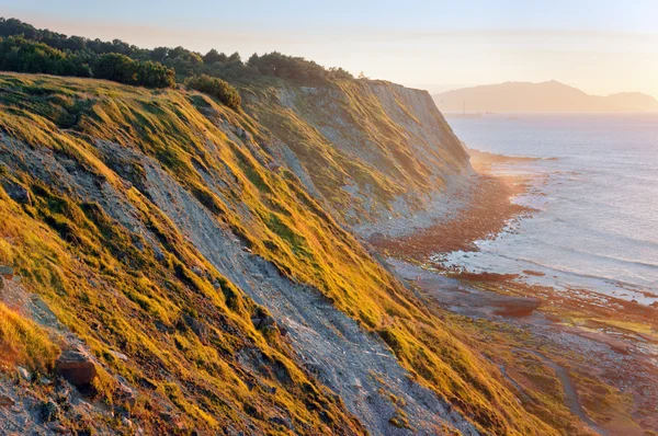 Cliffs of Azkorri beach at sunset — Stock Photo, Image