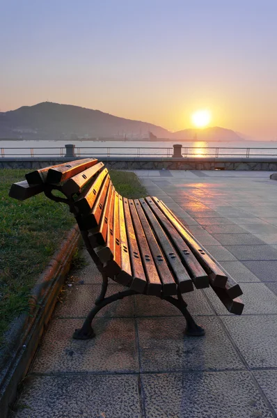 Bench on promenade at sunset — Stock Photo, Image