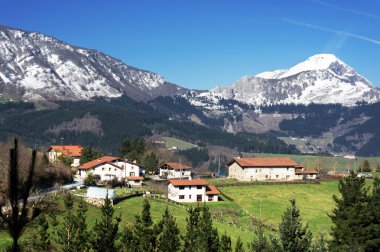 village in Aramaio valley, with snowy mountains. Basque Country. clipart