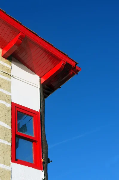 Fachada da casa com telhado vermelho e janela contra o céu azul — Fotografia de Stock