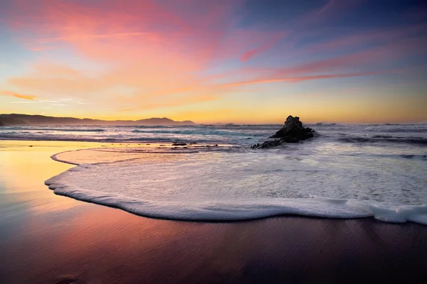 Vague mousse sur sable de plage au coucher du soleil — Photo
