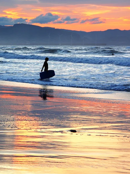 Surfer met boogie bestuur bij zonsondergang — Stockfoto