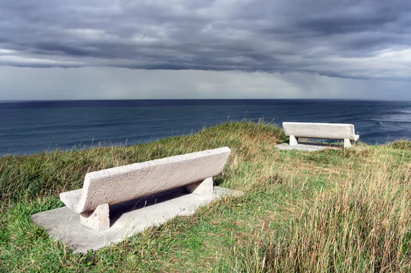 Benches on cliff near the sea with stormy clouds — Stock Photo, Image