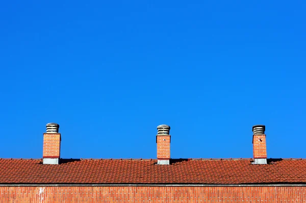 Skorstenar på hus tak mot blå himmel — Stockfoto