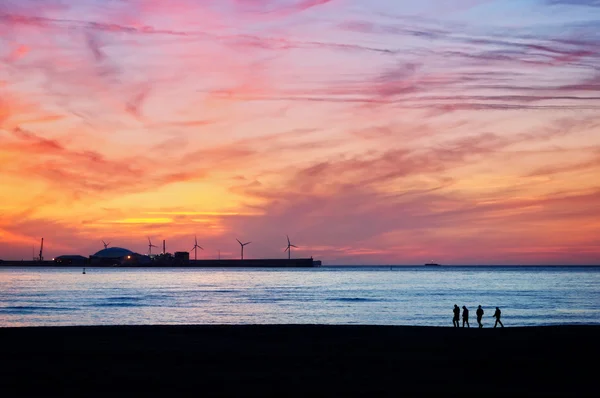 Vänner silhuett promenader på stranden vid solnedgången — Stock fotografie