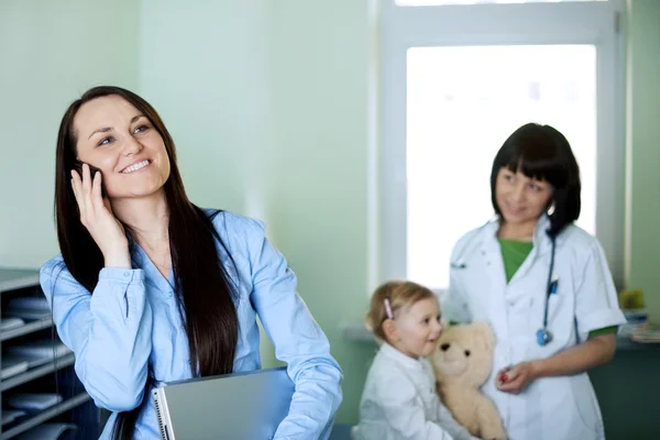 Drukke zakenvrouw nemen van haar dochter naar de dokter — Stockfoto