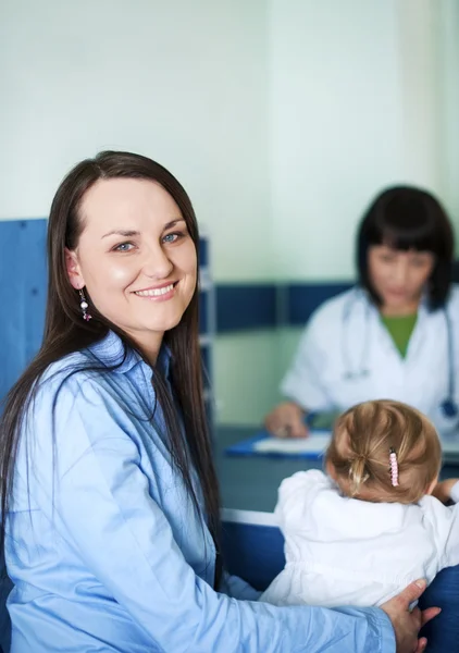 Sorridente madre con il suo bambino presso lo studio medico — Foto Stock