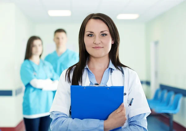 Portrait of young female doctor with interns in background — Stock Photo, Image