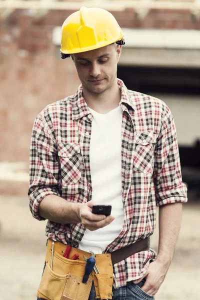 Bauarbeiter schreibt SMS auf Handy — Stockfoto