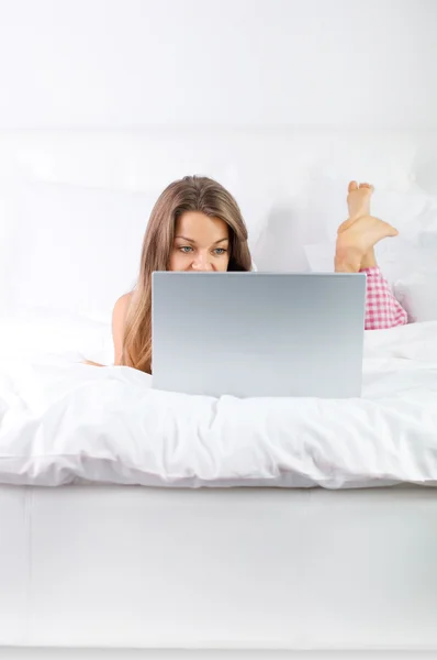 Jovem mulher usando laptop na cama — Fotografia de Stock